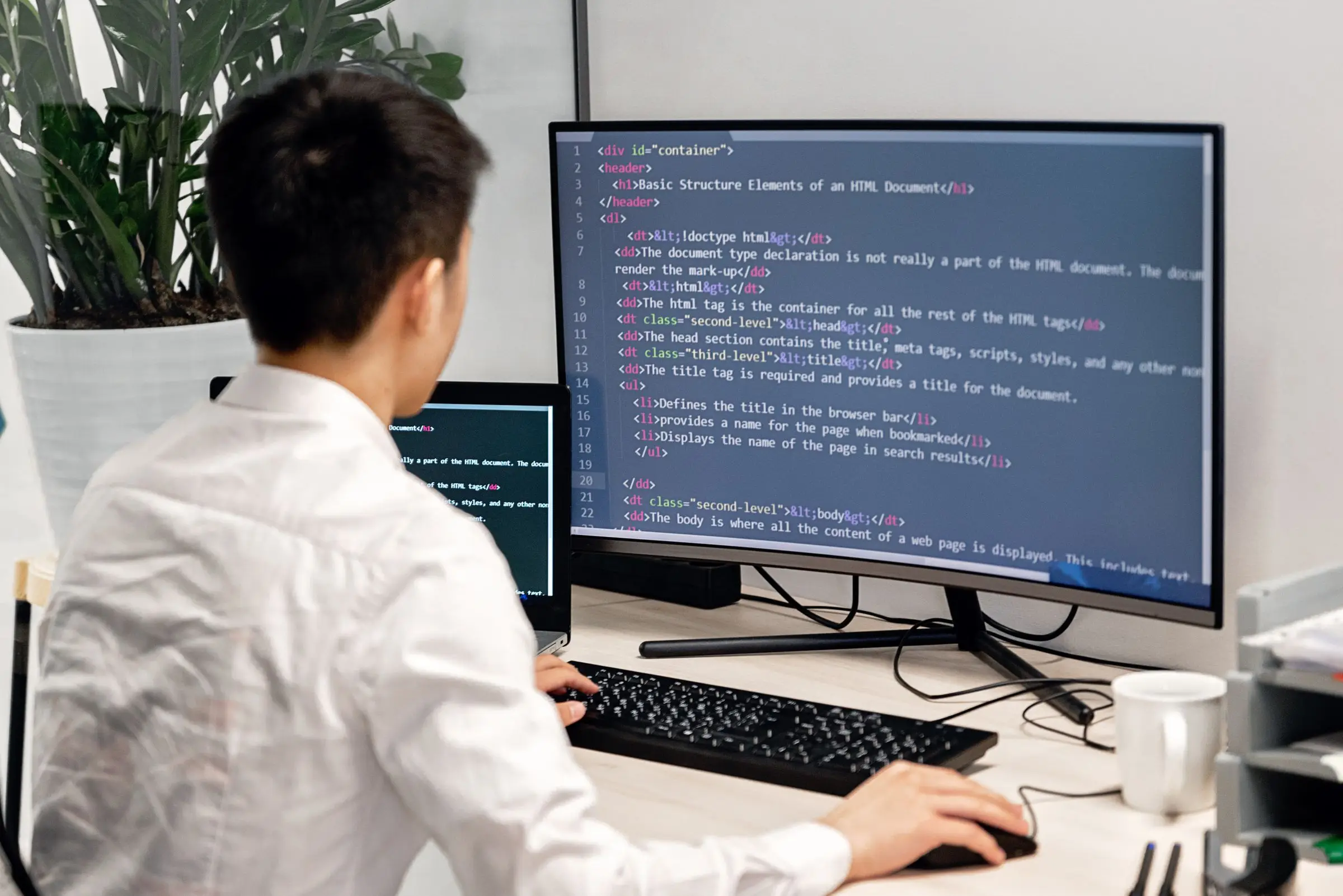 Person arbeitet an einem Bildschirm mit Quelltext in einem hellen Büro.