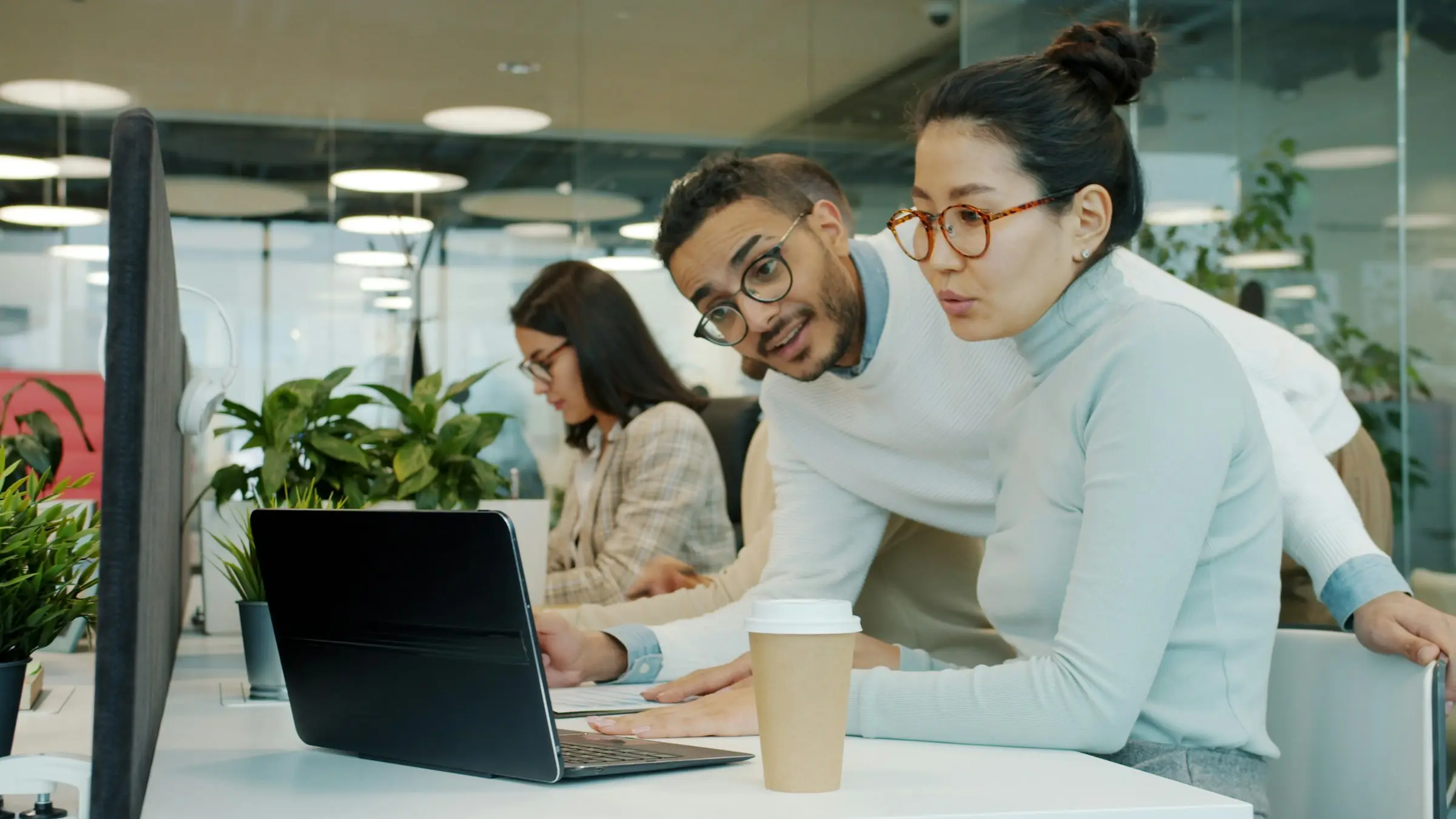 Zwei Kolleginnen und Kollegen besprechen im Büro etwas am Bildschirm.